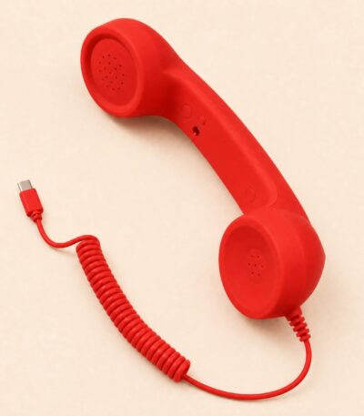 Red retro telephone handset connected to a smartphone